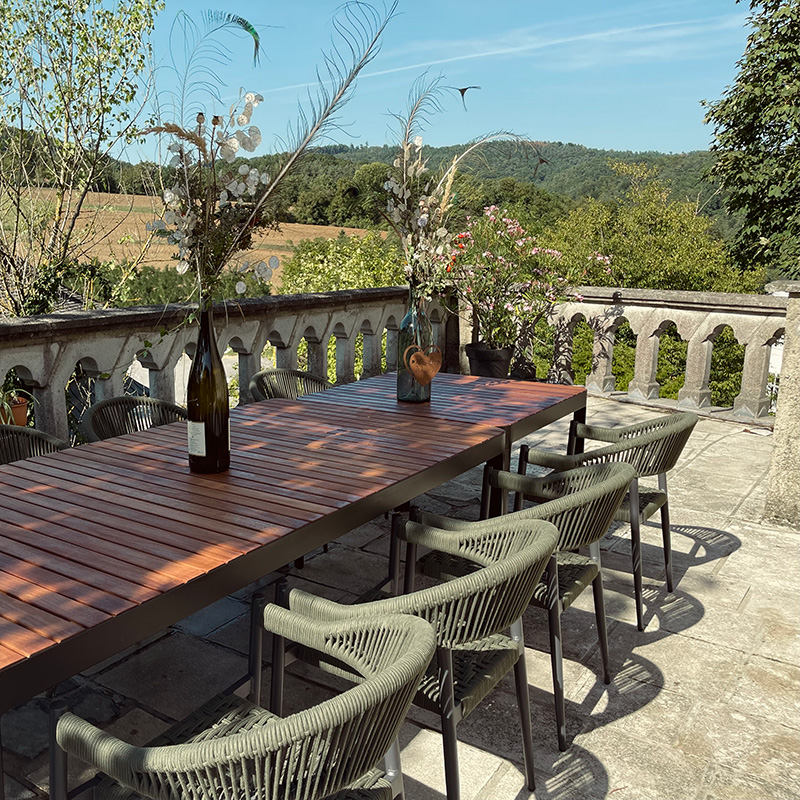 Gartentisch und Sessel auf der Terrasse mit Ausblick ins Grüne