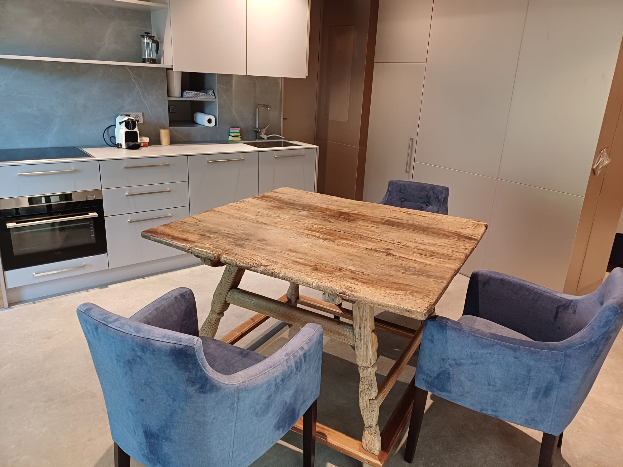 Eating table with 3 chairs next to a modern kitchen