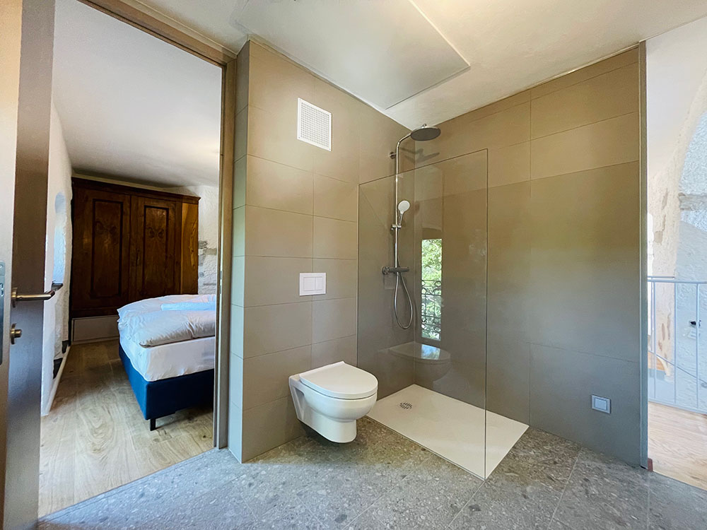 Accessible shower with toilet next to it and a door to the bedroom