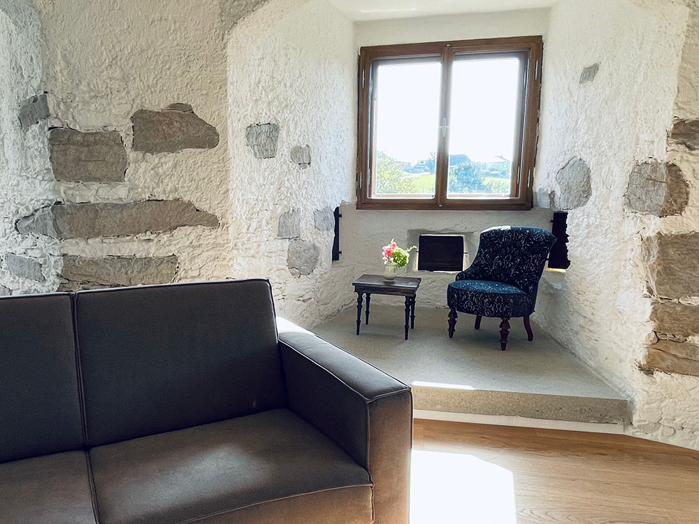 Sofa mit gemütlichem Sessel mit Tischchen vor Gewölbefenster