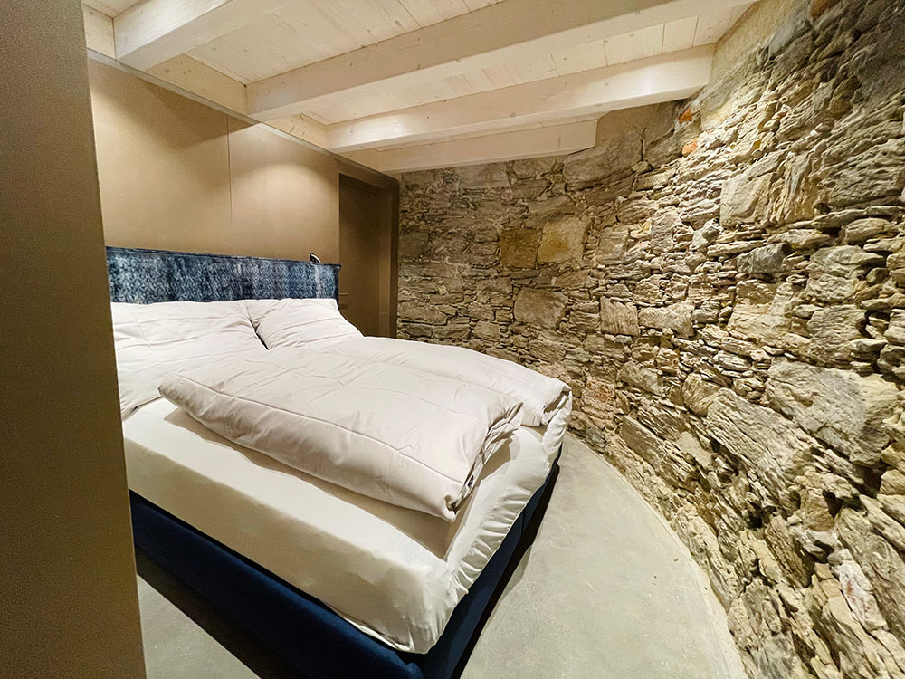 Schlafzimmer mit restaurierter Steinmauer als Wand